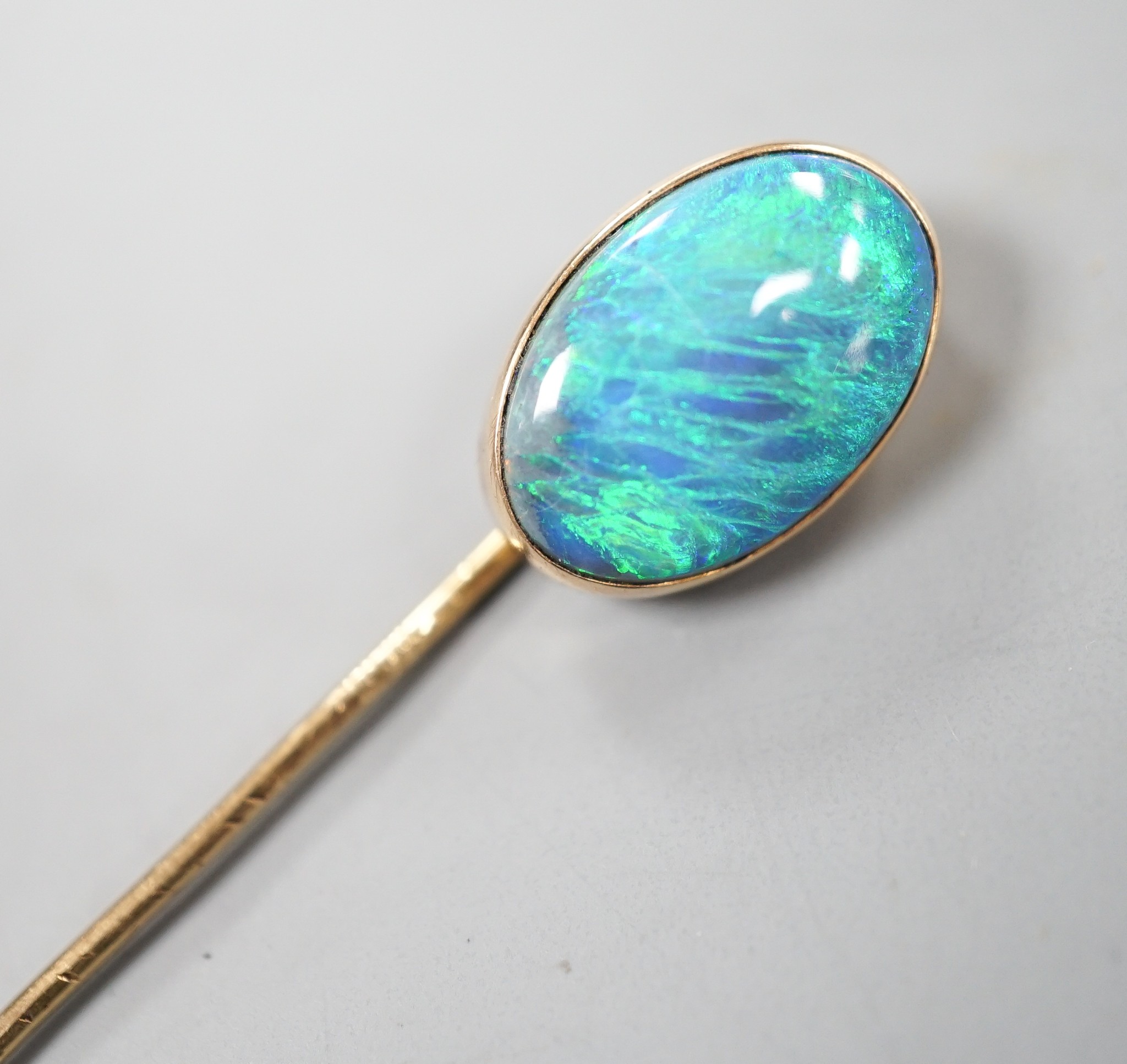 An Edwardian yellow metal and oval black opal set stick pin, 67mm, gross 2.7 grams